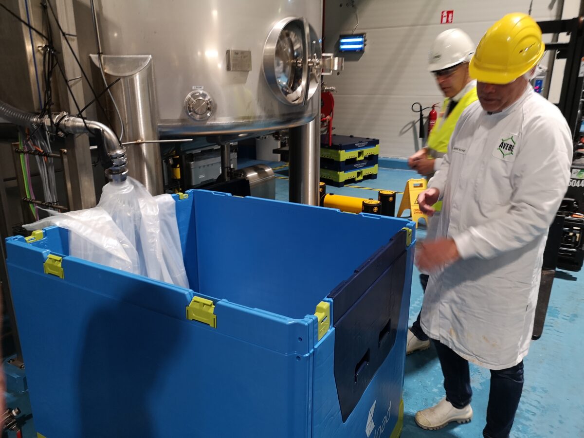 Factory workers prepare a Tosca Superior Hybrid IBC with a liner to be filled with liquid ingredients.