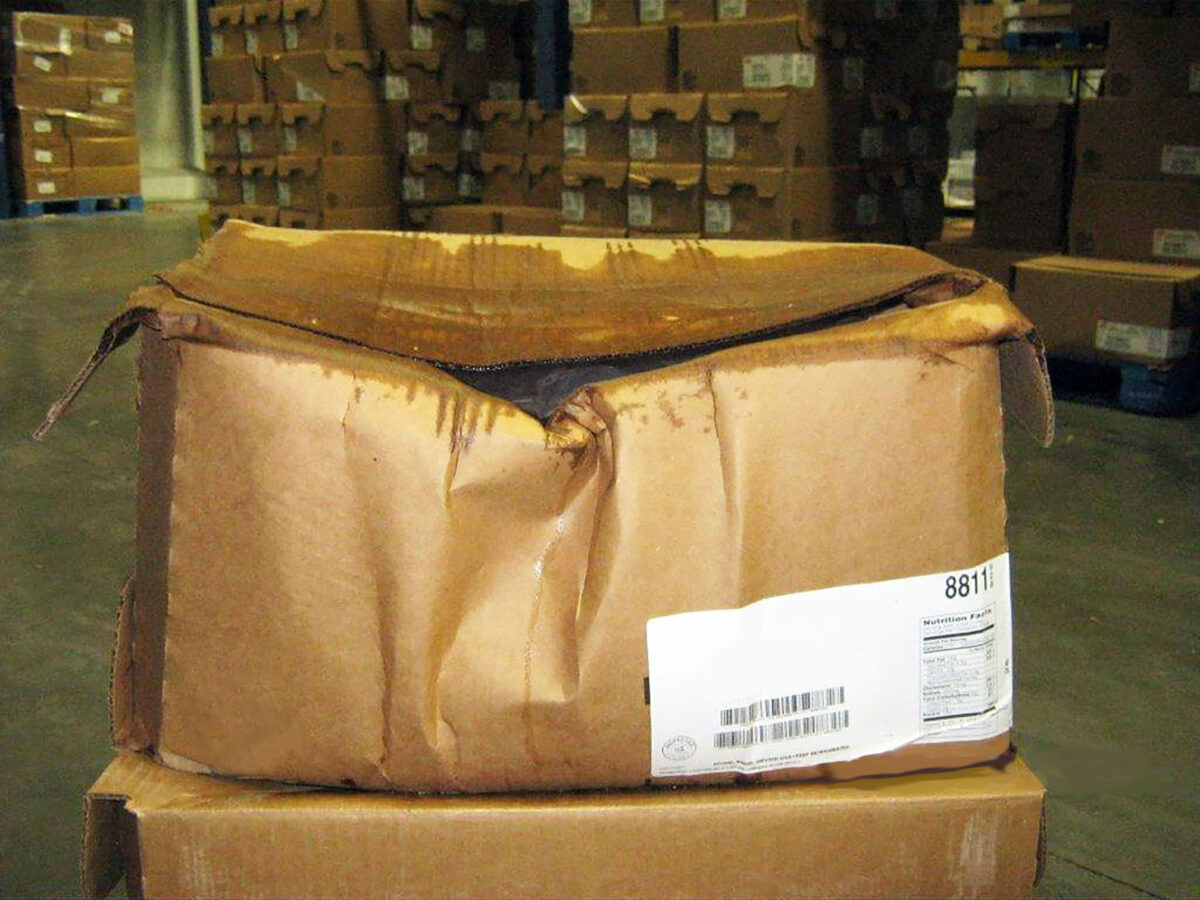 Crushed and soiled corrugated cardboard boxes used to package chicken indicate product damage that could have been avoided with reusable plastic poultry shipping boxes.