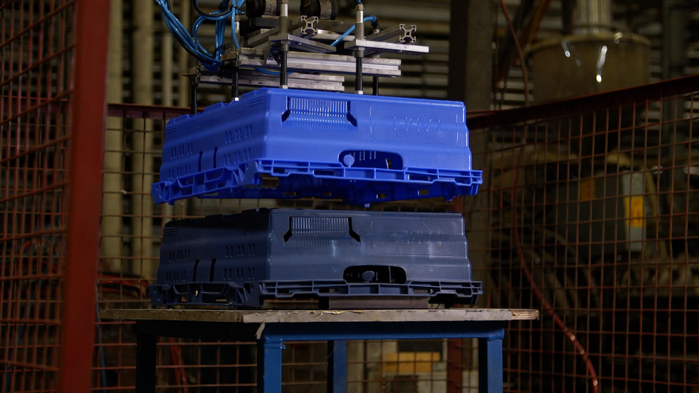 A blue custom Tosca crate being formed from a product mold by an automated machine in a production facility.