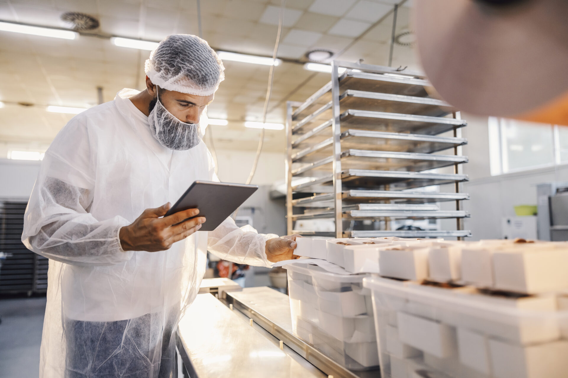 A food factory supervisor using tablet and assesses quality of food. It's an important factor in FSMA